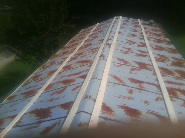Rusted metal roof panels with new wood purlins before replacement in South Charleston