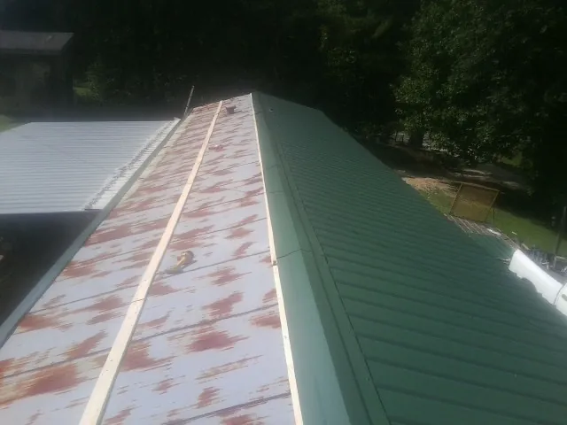 Old rusted panels beside newly installed green metal roofing — Wind Damage Roof Repair by Roofing Brothers in South Charleston