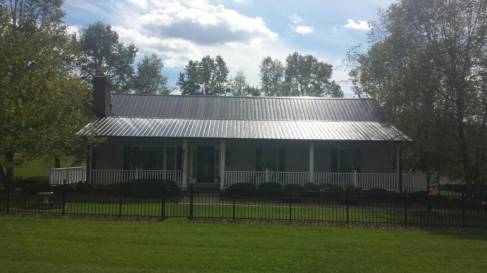 Gray metal roof on a brick ranch with a full width front porch — Gutter Guard Installation work by our crew in South Charleston