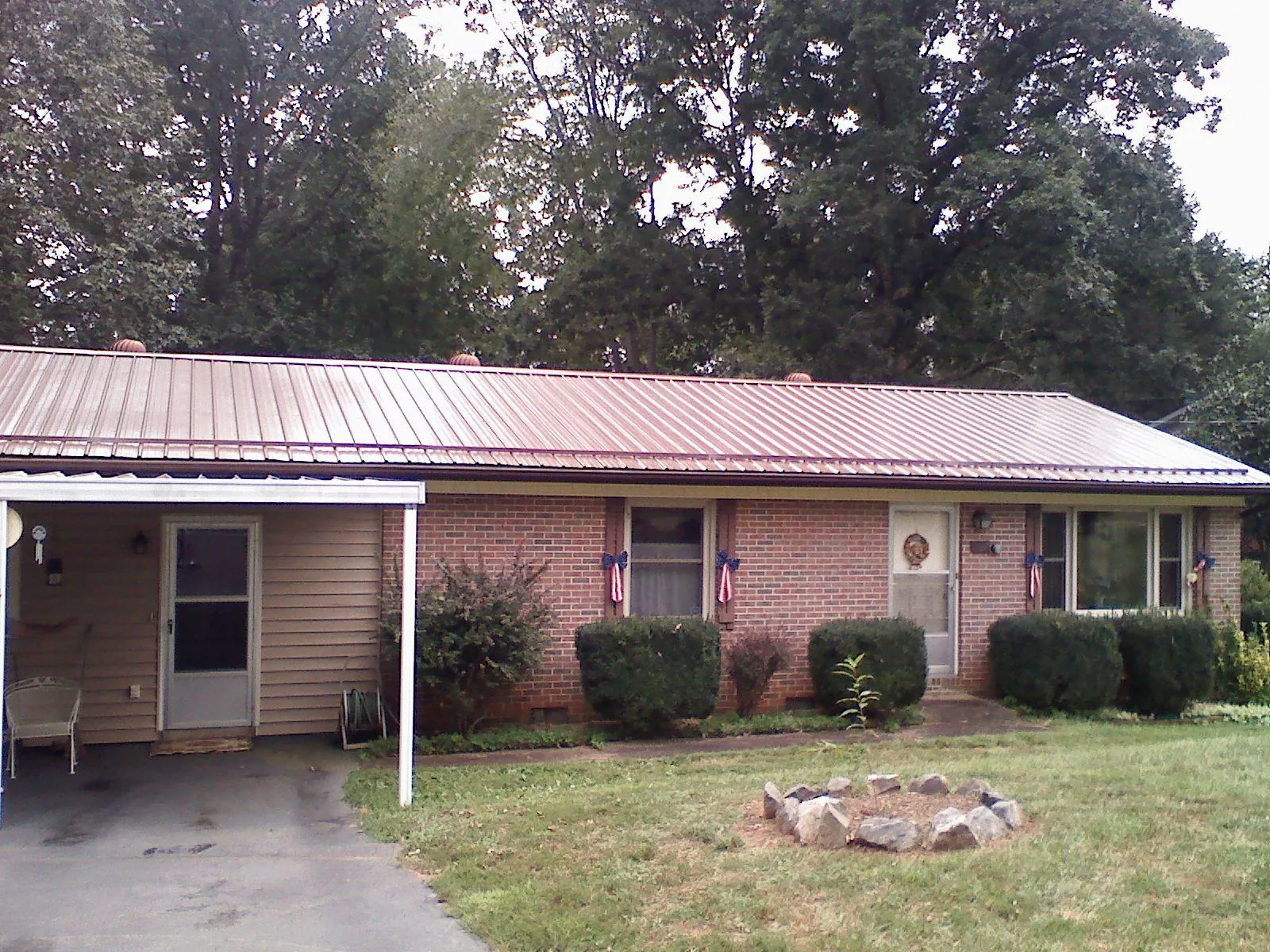 Bronze metal roof and carport on a brick ranch home — Roof Repair work by our crew in South Charleston