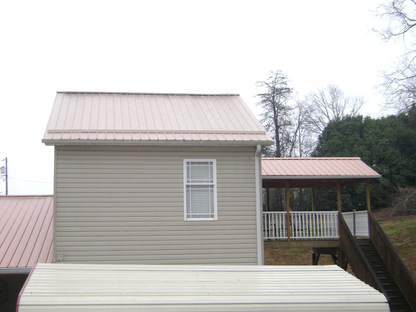 Tan metal roofs on a two story addition and attached porch, from a Roof Replacement job in South Charleston