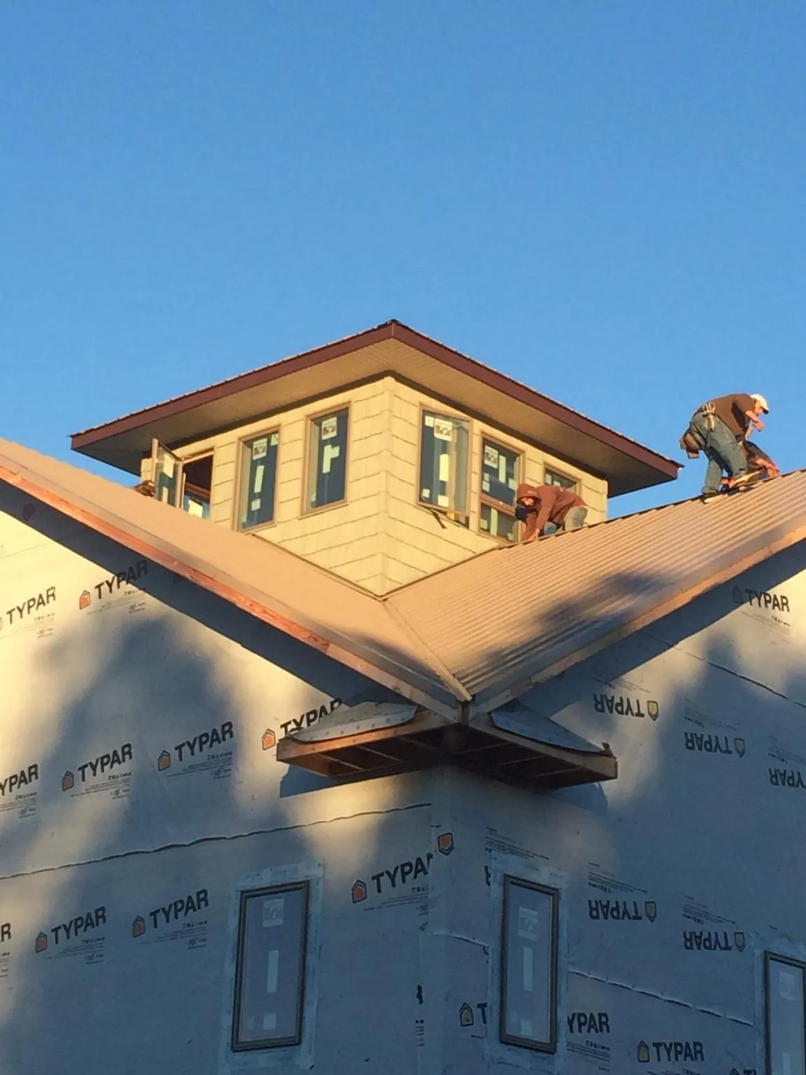 Roofers working around a rooftop cupola on a new metal roof at sunset — Roof Waterproofing in South Charleston by Roofing Brothers